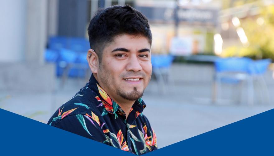 Miguel, a person sitting outside the front of the lane center building in a hawaiian shirt with legs crossed. 