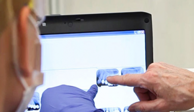 A dentist and assistant looking at dental x-rays on a screen