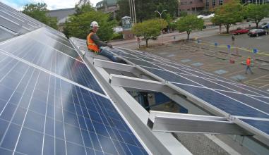 person in hardhat and orange vest installing solar panels 