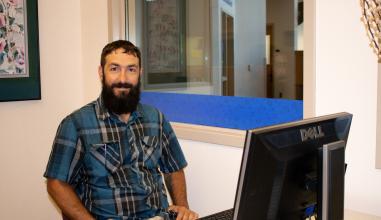 A friendly student worker at a computer