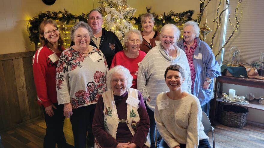 9 members of the senior companion program smiling and posing at a holiday party