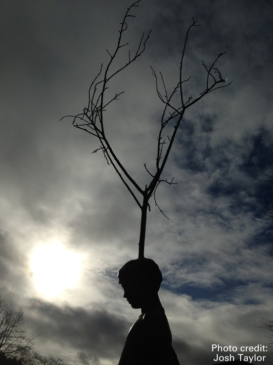a brooding statue in front of a cloudy sky
