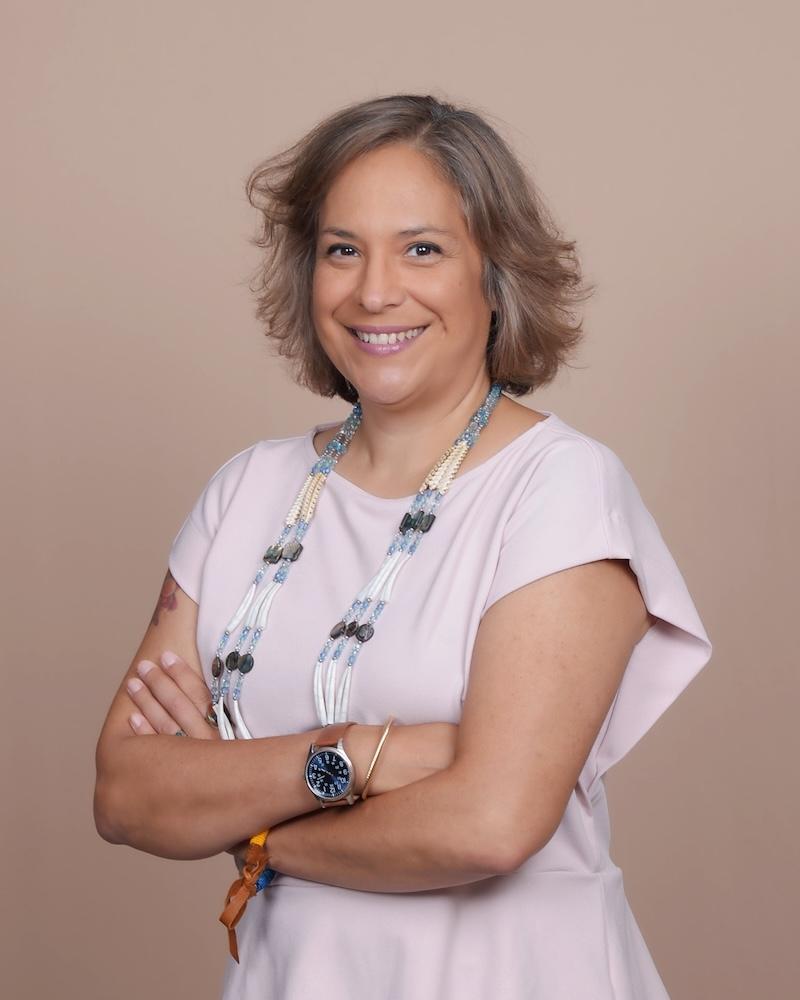 Longhouse Steward Cohen-Rencountre, a Native American woman with a very warm smile, short gray hair, and a beaded necklace 