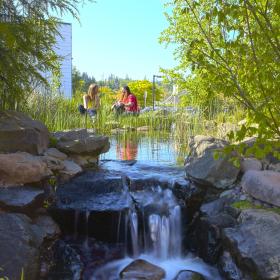 two people sitting in front of a tiny waterfall made on campus