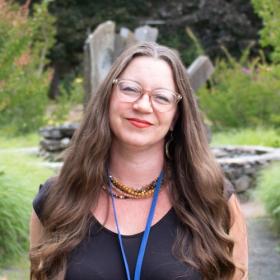 College Achievement Coach Deidra Little, a friendly woman with long hair, red lipstick, and stylish glasses