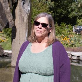College Achievement Coach Tina Hunter, an friendly older woman with pretty green dress and sunglasses