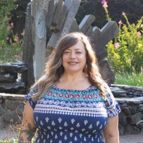 College Achievement Coach Eila Sontag, a friendly, stylish woman in blue summer dress