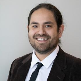 a man in his 30s with long hair and a short beard, brown eyes, and a cool corduroy blazer