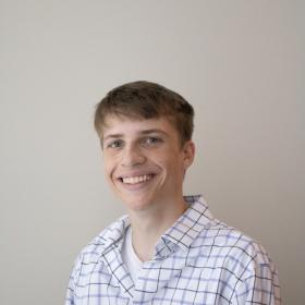 a young man in a button up shirt with a wide, friendly smile