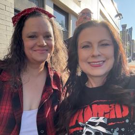 Health Clinic admins Danielle Nichols and Frankie Cocanour smiling together at a punk rock concert