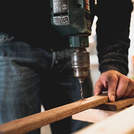 Construction worker drilling a hole in a board