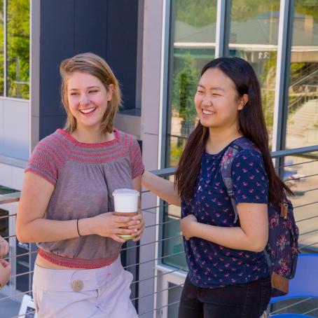 happy students with backpacks and coffee smiling and talking