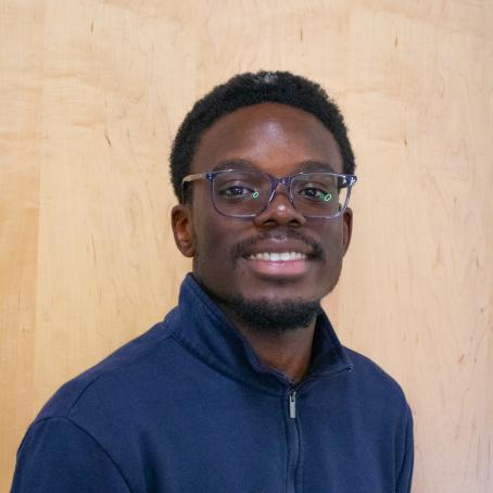 a young Black man with glasses and a big smile