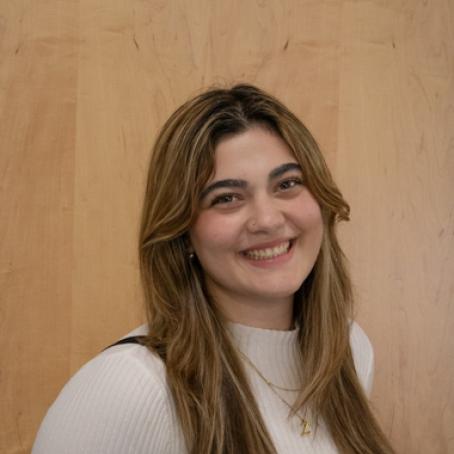 A young Middle Eastern woman with a big smile and highlights in her long hair