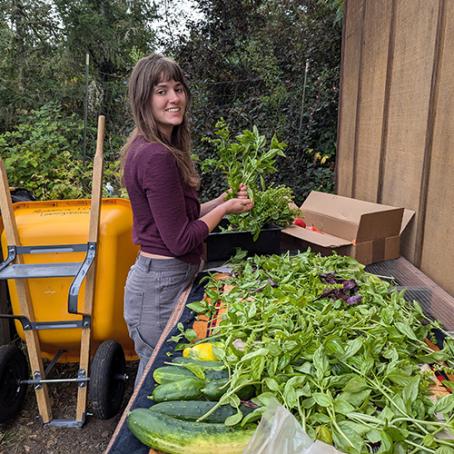 Ellie, a student worker, cleaning produce in the learning garden to donate to the food pantry