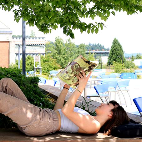 a student reading a book outside the center building