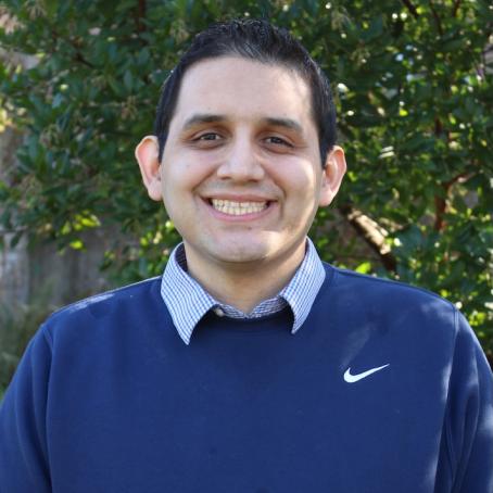 Fernando Rivas, a tall Latino man with a friendly smile, wearing a blue sweater