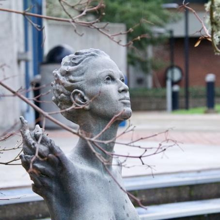 a stone statue of a woman with wings looking up to the sky as seen on campus outside the Ragazzino Theatre