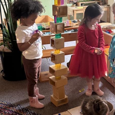 three little girls, one Black and two white, play with building blocks in the colorful Lane Child and Family Center