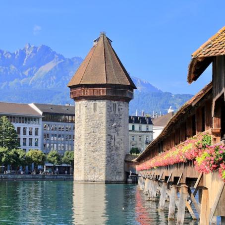 a beautiful covered bridge over a lake in Lucerne, Switzerland with mountains in the background 