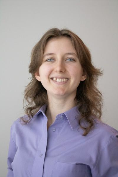 a young woman with a lilac button up shirt, bright blue eyes, and wavy dark blonde hair