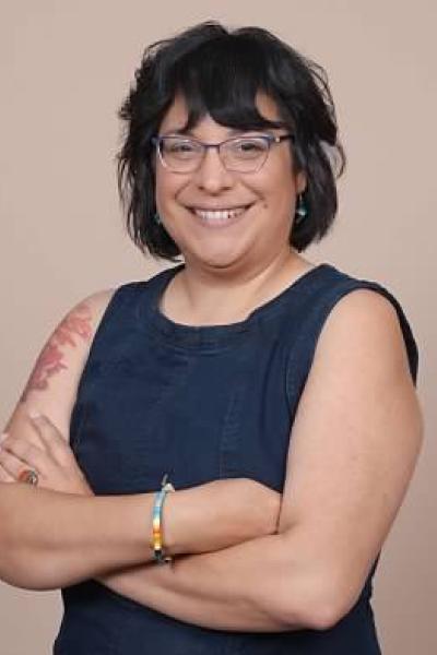 Longhouse Steward Cohen-Rencountre, a Native American woman with a friendly smile, glasses, and an upper arm tattoo