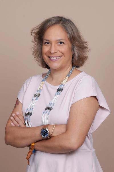 Longhouse Steward Cohen-Rencountre, a Native American woman with a very warm smile, short gray hair, and a beaded necklace 