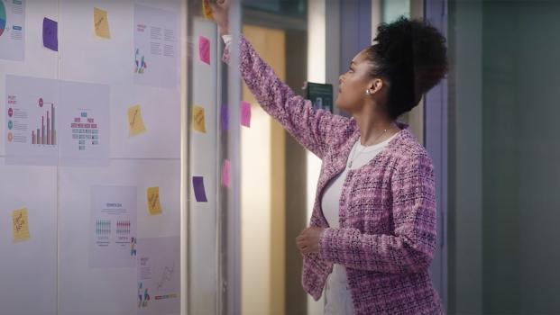business student putting sticky notes on whiteboard