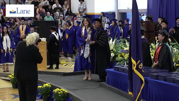 President Bulger awards a diploma to a smiling nursing student at the 2026 Commencement