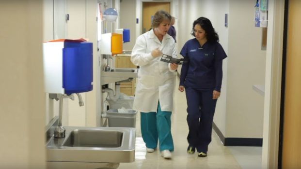 a dentist and assistant walk down a clinic hall