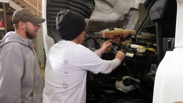 two diesel technology students repair a semi-truck engine